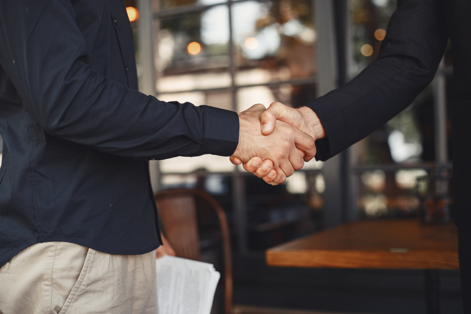 Two professionals shaking hands, symbolizing borrower trust built through mortgage lending software.